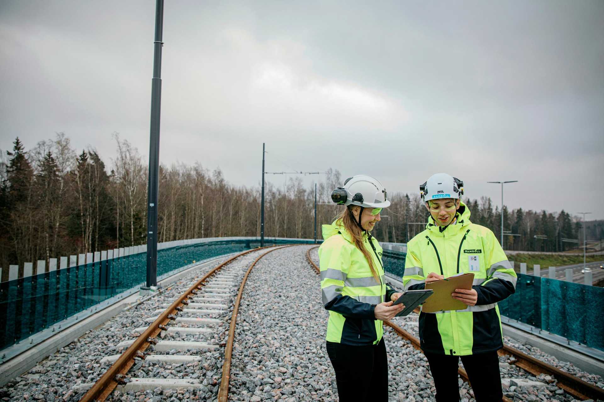 RFI brand picture photoshoot in Espoo, Finland. Taken in October 2021. In the picture a man stands on a bridge on Ring I motorway in Espoo wearing a high-visibility jacket and helmet, looking at a tablet computer.