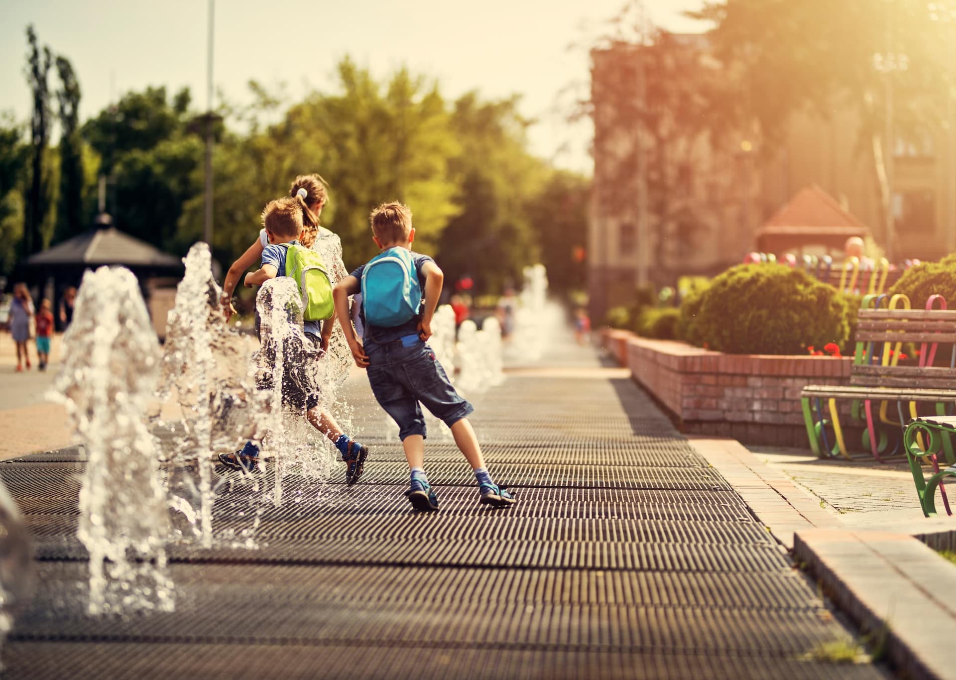 Hot summer day in the city. School children are having fun playing in the city fountains after school.